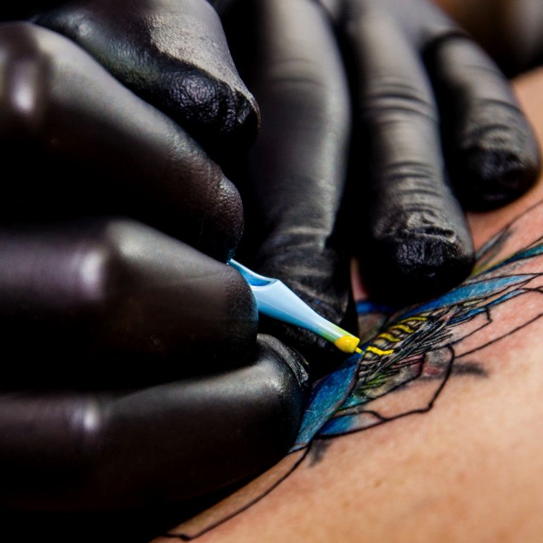 Gloved hand packing blue colour into fresh linework